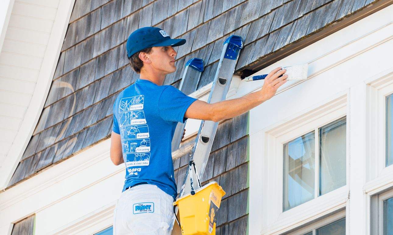 A Surv employee painting a house