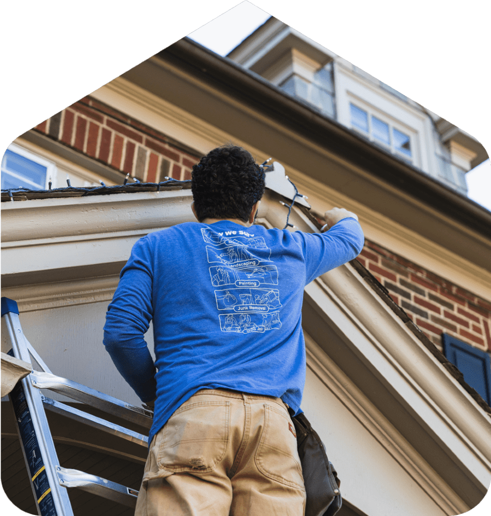 A Surv employee hanging string lights from a roof