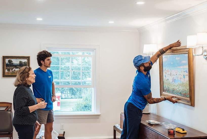 A worker hanging a painting