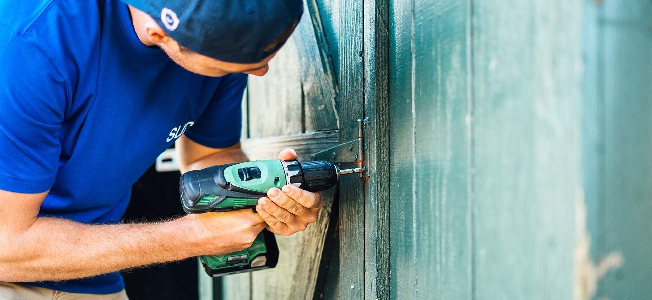 A Surv employee drilling screws into a fence hinge